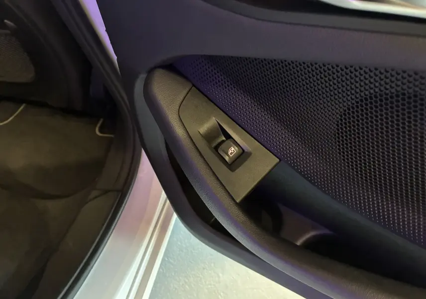 Bouton de commande de lève-vitre sur la porte avant gauche d'une BMW Série 1 blanche édition sport 2023.