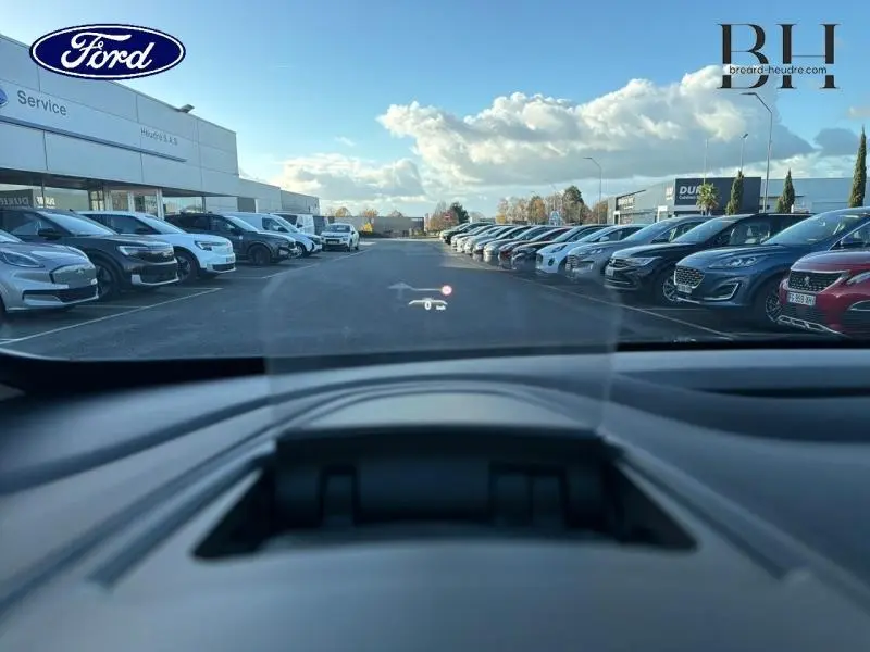 Affichage tête haute visible depuis l'habitacle d'un Renault Espace gris Cassiopée, vue avant sur parking extérieur.