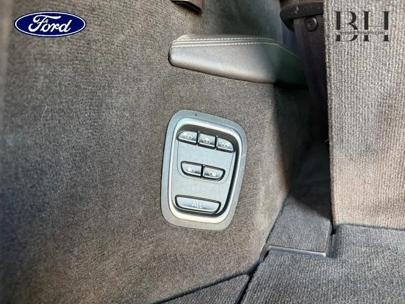 Gros plan sur les commandes de réglage des sièges arrière sur la moquette gris foncé d'un Renault Espace Gris Cassiopée.