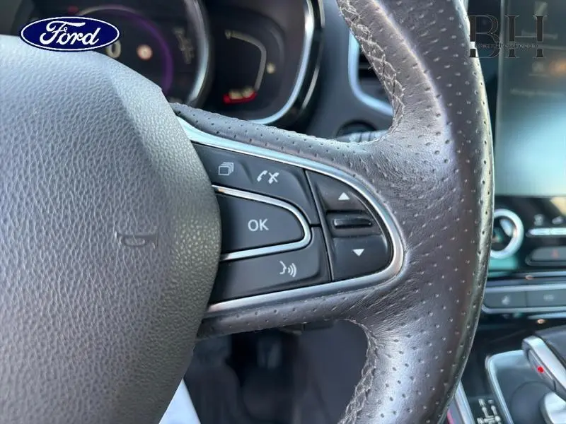 Gros plan sur le volant cuir perforé côté droit du Renault Espace Gris Cassiopée avec commandes multifonctions visibles.