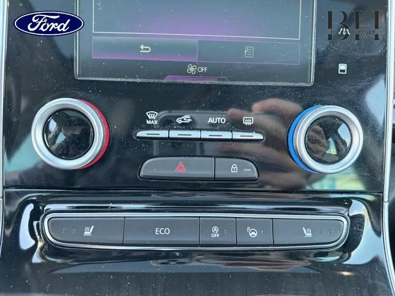 Gros plan sur la console centrale noire brillante de la Renault Espace gris Cassiopée, avec commandes climatisation et boutons multifonctions.