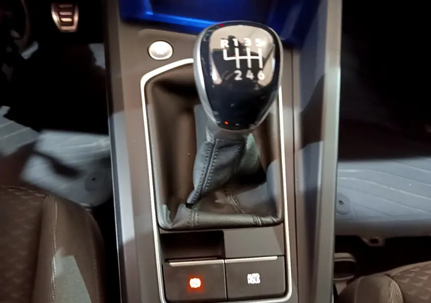 Gros plan sur levier de vitesse manuel noir dans console centrale d’une Volkswagen Golf 1.0 TSI bleu 2022