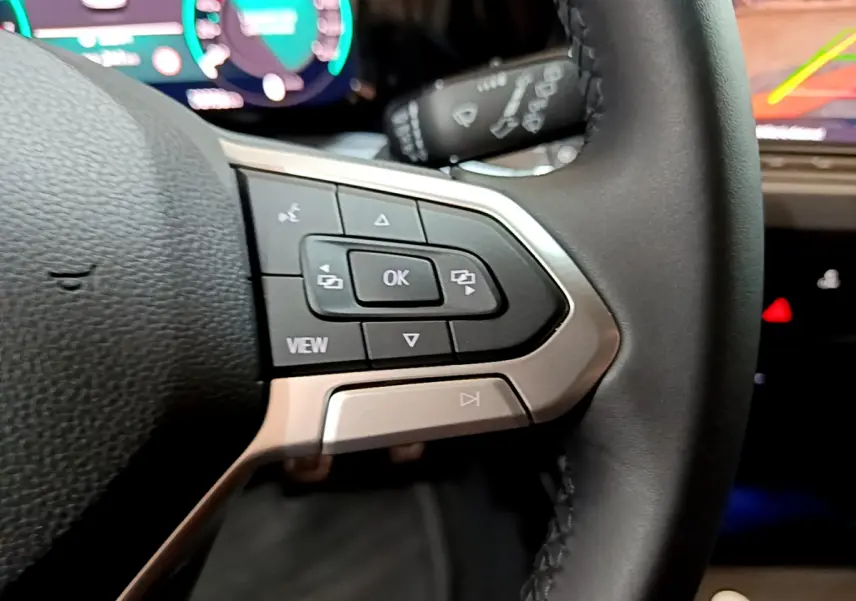 Gros plan sur les commandes au volant côté gauche d'une Volkswagen Golf bleu 2022 avec affichage numérique en arrière-plan.