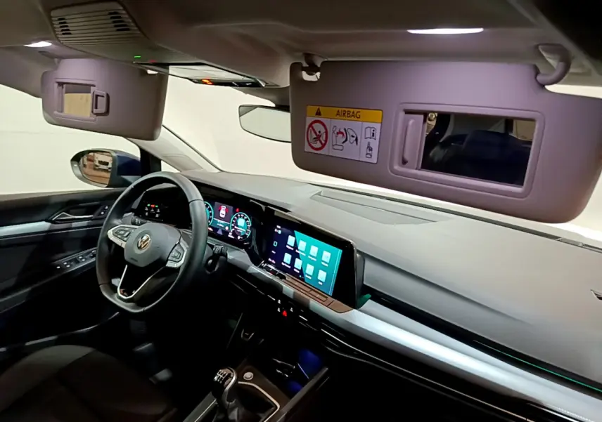 Intérieur avant gauche de la Volkswagen Golf 1.0 TSI bleu, tableau de bord digital et volant cuir multifonctions visible.