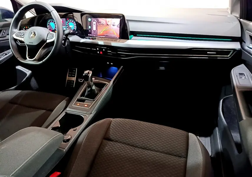 Intérieur de la Volkswagen Golf 1.0 TSI 2022, vue avant côté conducteur, tableau de bord noir avec éclairage bleu.