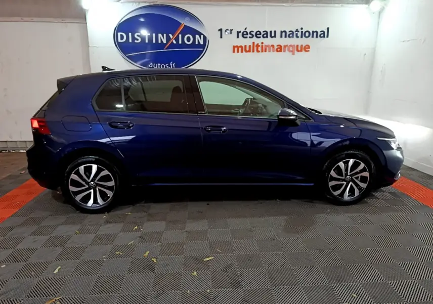 Profil droit d'une Volkswagen Golf 1.0 TSI bleu foncé stationnée en intérieur avec jantes alliage distinctives.