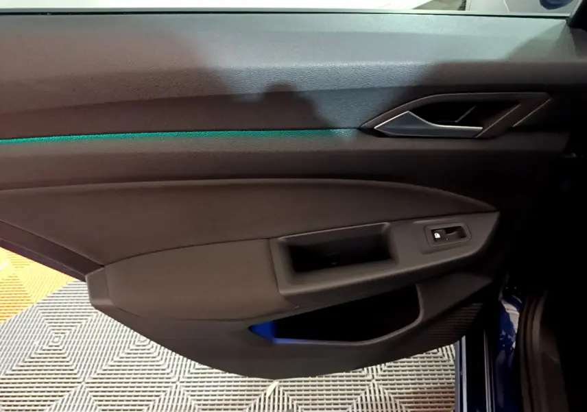 Vue rapprochée de la porte côté gauche de la Volkswagen Golf bleue 2022, avec éclairage d'ambiance vert subtil.