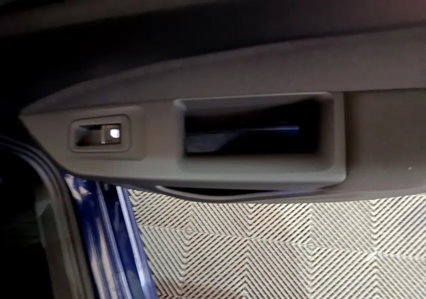 Poignée intérieure de porte côté gauche d'une Volkswagen Golf 2022 bleu, avec bouton de verrouillage visible.