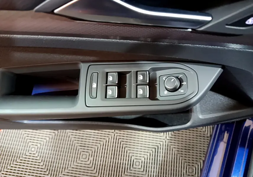 Vue rapprochée du panneau de commandes des vitres et rétroviseurs côté conducteur d'une Volkswagen Golf bleue 2022.