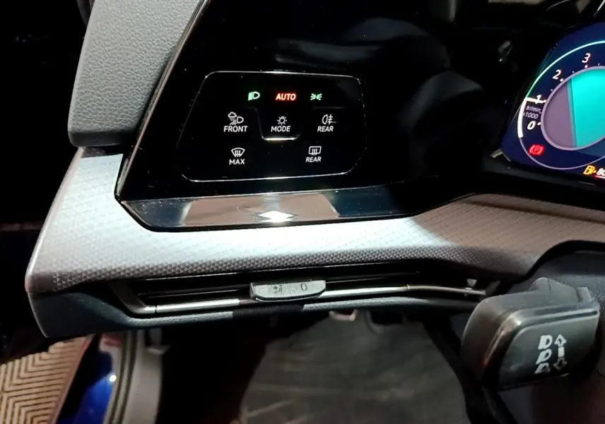 Détail du panneau de commande d'éclairage avec affichage digital sur tableau de bord d'une Volkswagen Golf bleue 2022.