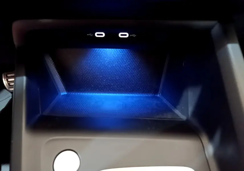Gros plan sur la zone de recharge à induction éclairée en bleu dans le compartiment central d'une Volkswagen Golf bleue 2022.
