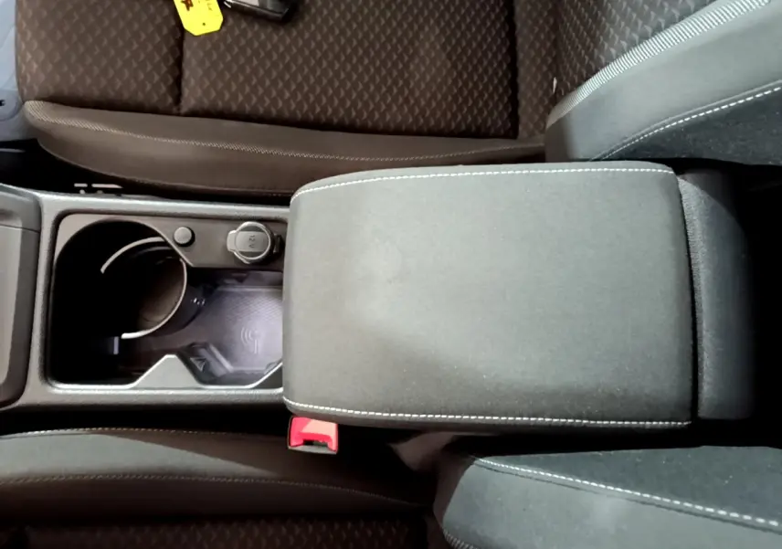 Vue plongeante sur la console centrale noire de la Volkswagen Golf 1.0 TSI avec accoudoir et prise 12V visible.