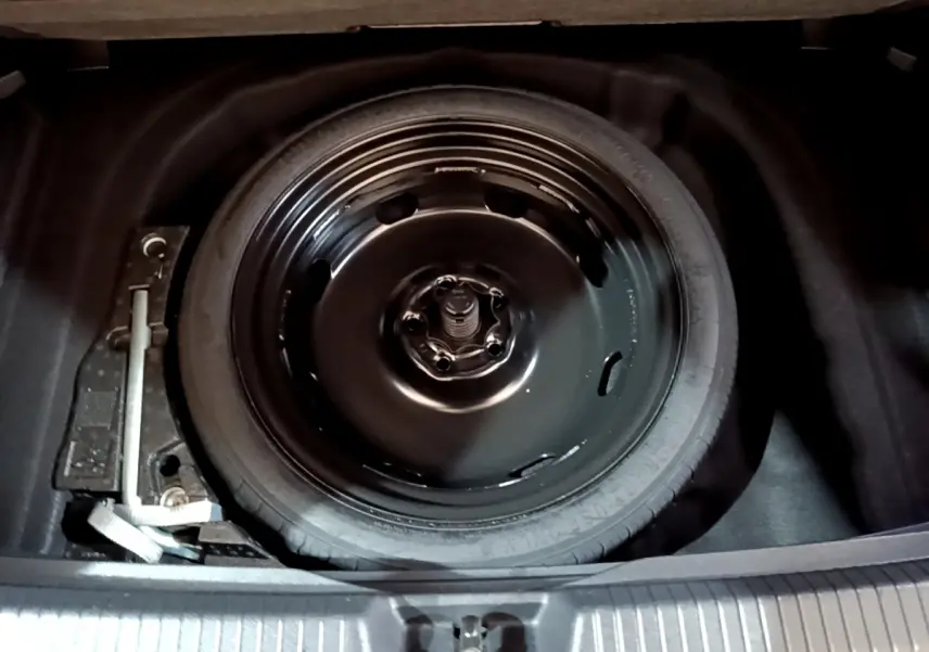 Gros plan sur la roue de secours noire dans le coffre d'une Volkswagen Golf 1.0 TSI bleu 2022.