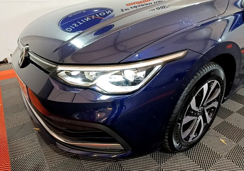 Vue 3/4 avant droit d'une Volkswagen Golf 1.0 TSI bleu avec phares LED et jantes alliage distinctives.