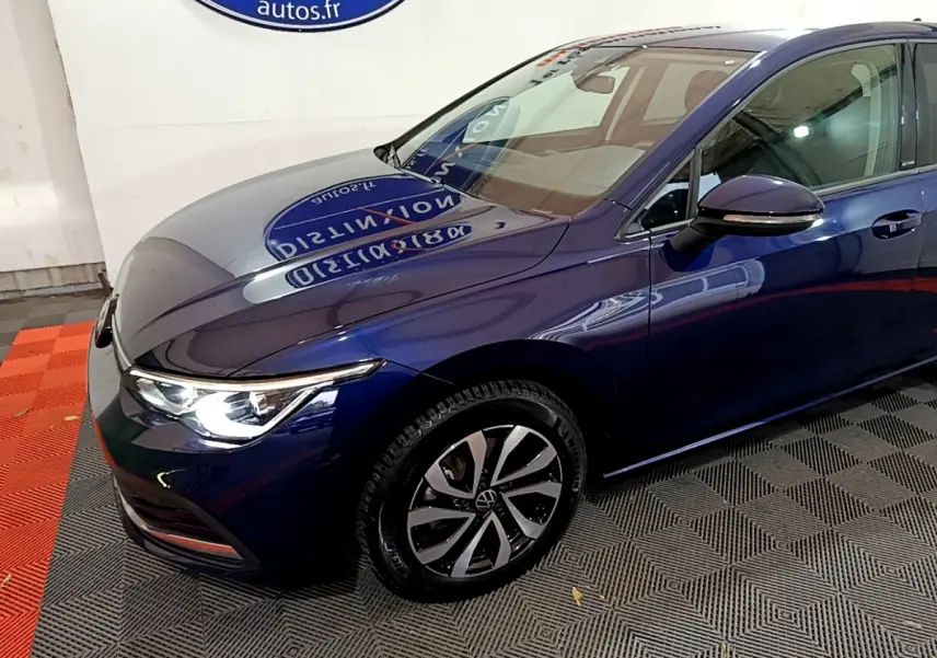 Vue 3/4 avant droit d'une Volkswagen Golf bleu métallisé avec phares LED allumés et jantes alliage distinctives.