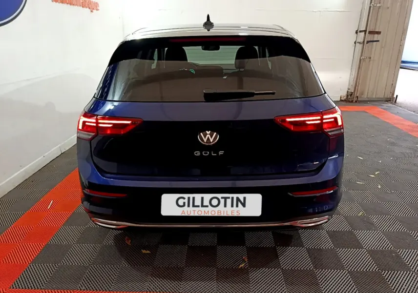 Vue arrière d'une Volkswagen Golf bleu 2022 avec feux LED allumés et logo VW visible sur le hayon.