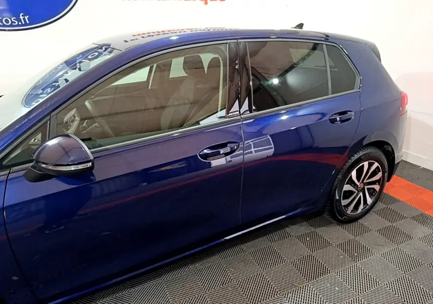 Vue latérale côté gauche d'une Volkswagen Golf 1.0 TSI Active bleu avec jantes alliage et vitres teintées.
