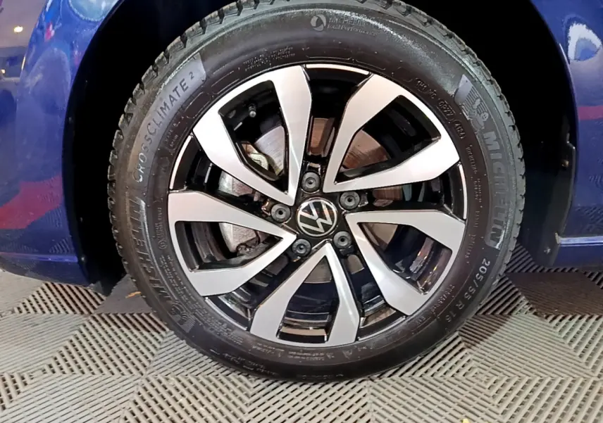 Gros plan sur la roue avant gauche d'une Volkswagen Golf bleu 2022 avec jante alliage bicolore et pneu Michelin.
