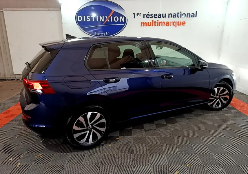 Volkswagen Golf 1.0 TSI bleu vue de profil côté gauche dans un showroom avec logo Distinxion en arrière-plan