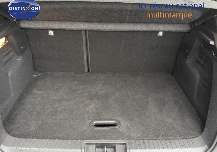 Coffre ouvert vu de face d'un Renault Captur 2025, intérieur noir avec tapis de sol en tissu.