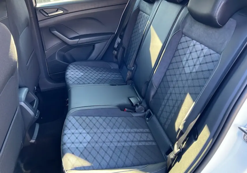Vue intérieure côté droit sur la banquette arrière tissu gris foncé à motifs géométriques du Volkswagen T-Cross blanc pur 2025.