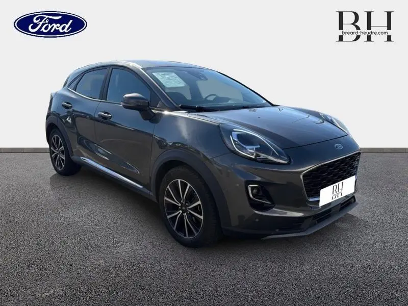 Ford Puma 2024 gris métallisé en 3/4 avant droit, avec jantes noires et vitres arrière surteintées.