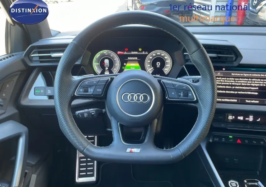 Vue intérieure centrée sur le volant noir perforé de l'Audi A3 Sportback 2025 avec tableau de bord numérique et écran tactile.