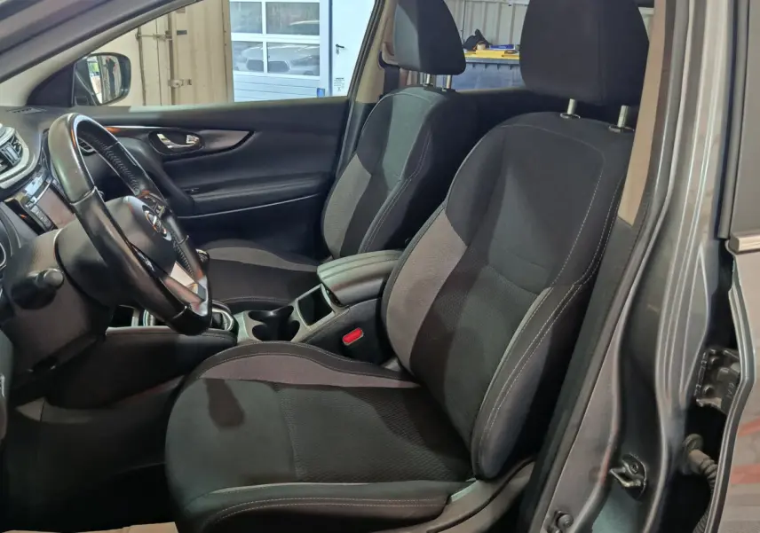 Intérieur du Nissan Qashqai gris clair, vue côté gauche sur sièges avant noirs et volant cuir multifonctions.