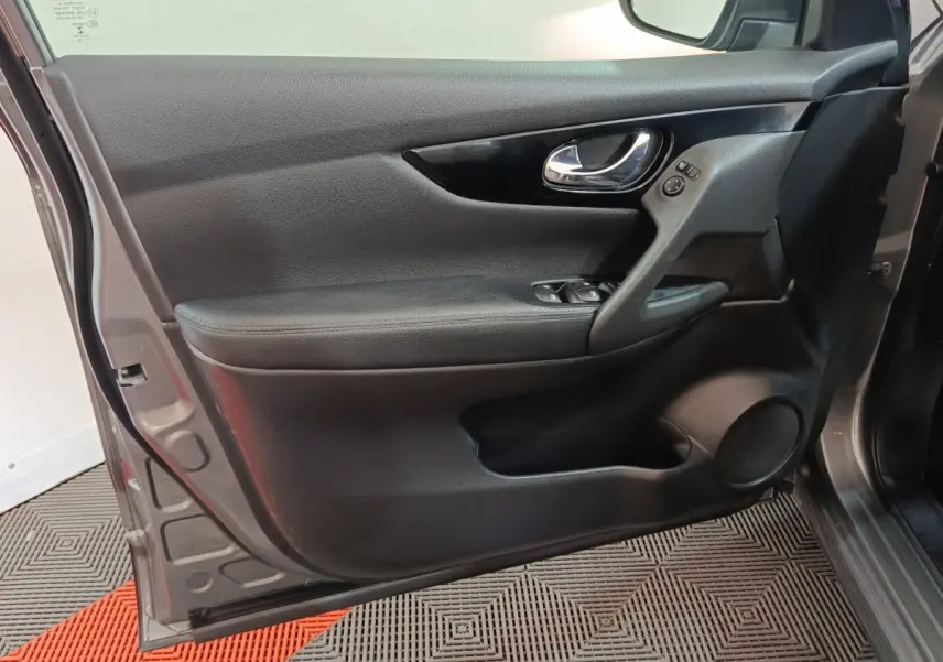 Porte avant gauche ouverte d'un Nissan Qashqai gris clair 2019, montrant la garniture intérieure noire et les commandes électriques.