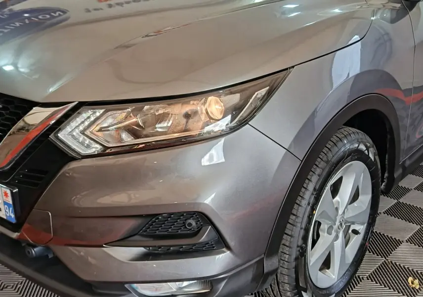 Gros plan sur l'avant droit gris clair du Nissan Qashqai 2019, mettant en valeur le phare et la roue.