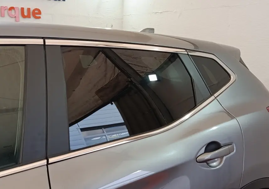 Gros plan sur la porte arrière côté droit d'un Nissan Qashqai gris clair avec poignée intégrée et vitres teintées.
