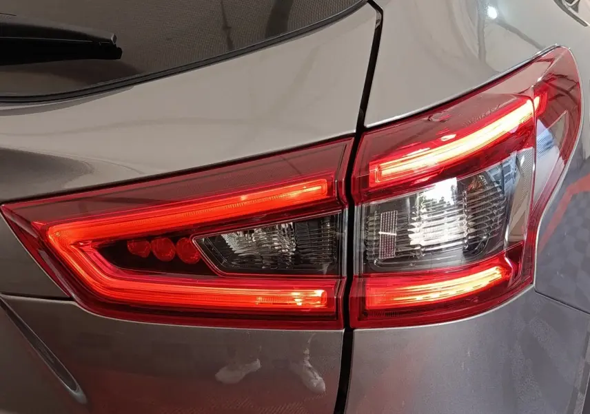 Gros plan sur le feu arrière droit rouge et blanc d'un Nissan Qashqai gris clair de 2019.