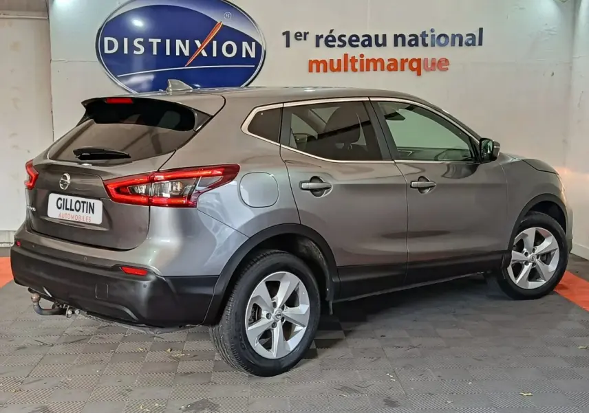 Nissan Qashqai gris clair vu de côté droit arrière, avec feux arrière allongés et jantes alliage cinq branches.