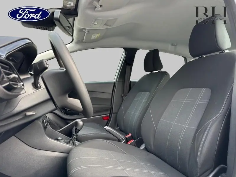 Vue intérieure côté conducteur de la Ford Fiesta gris lunaire, montrant les sièges avant en tissu noir à motifs gris.