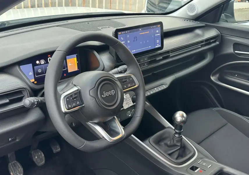 Vue intérieure côté conducteur du Jeep Avenger 2024, montrant le volant, tableau de bord numérique et levier de vitesse manuel.