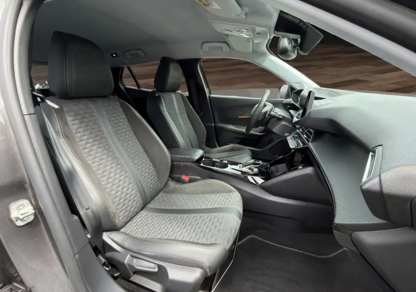 Vue intérieure côté gauche du Peugeot 2008 gris foncé, montrant les sièges avant en tissu et cuir avec surpiqûres contrastées.