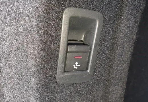 Gros plan sur le bouton de rabattement des sièges arrière dans le coffre d'une Audi A4 Avant Business gris Terra 2020.