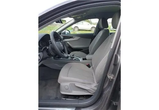 Vue intérieure côté conducteur de l'Audi A4 Avant Business 30 TDI gris Terra, montrant les sièges et le tableau de bord moderne.