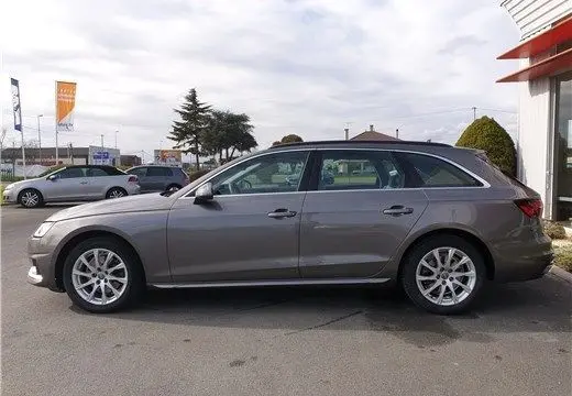 Audi A4 Avant Business gris Terra vue de profil côté gauche, stationnée sur un parking extérieur.
