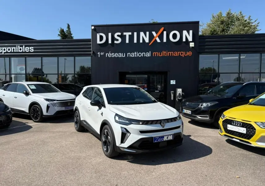 Renault Symbioz blanc nacré en 3/4 avant droit, avec calandre noire et jantes 18 pouces devant un showroom Distinxion.