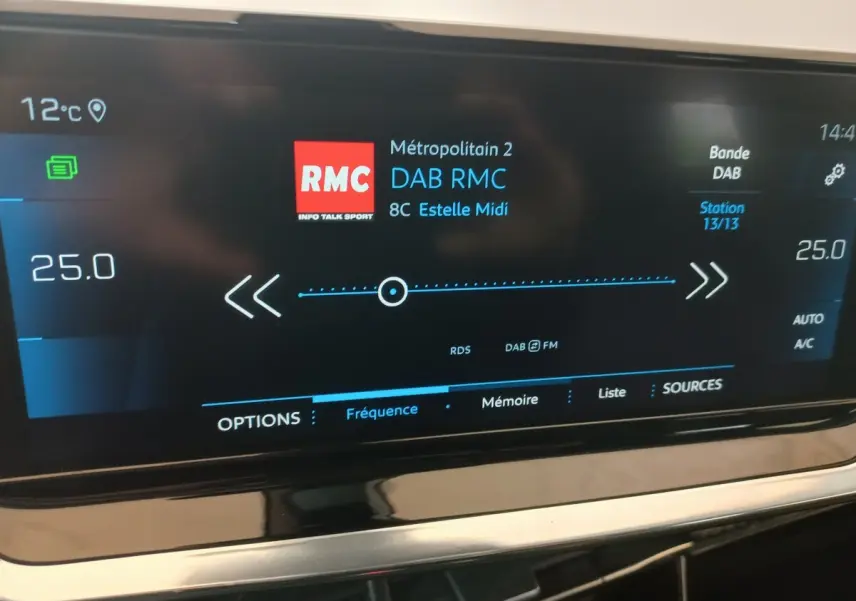 Écran tactile central du tableau de bord du Peugeot 2008 orange, affichant la radio DAB RMC et la climatisation à 25°C.