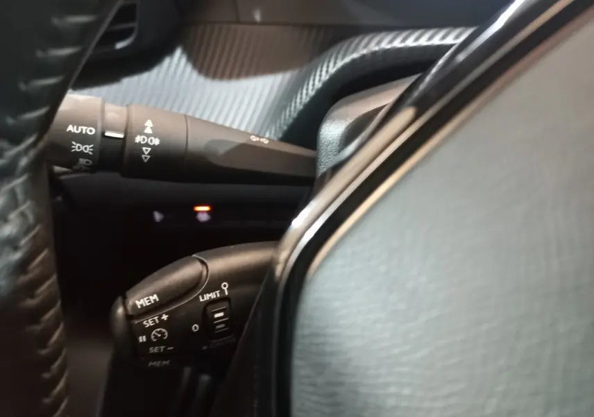 Gros plan sur les commandes au volant du Peugeot 2008 2021, avec cuir noir et boutons multifonctions visibles.