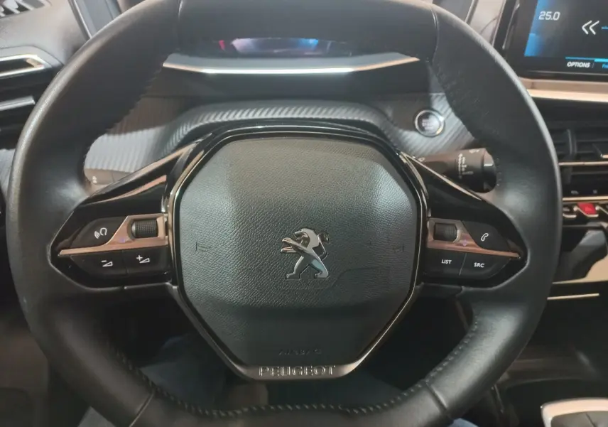 Volant cuir noir de Peugeot 2008 2021 avec commandes intégrées et tableau de bord numérique partiellement visible.