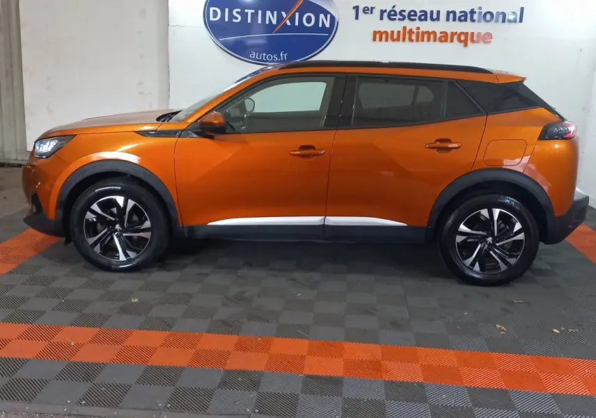 Profil côté gauche d'un Peugeot 2008 orange 2021, finition Allure Business, avec jantes noires et toit noir contrasté.