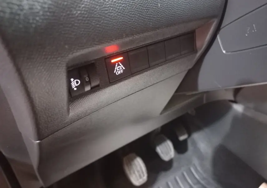 Gros plan sur les commandes sous le tableau de bord côté gauche du Peugeot 2008 orange, avec témoin d'alerte allumé.