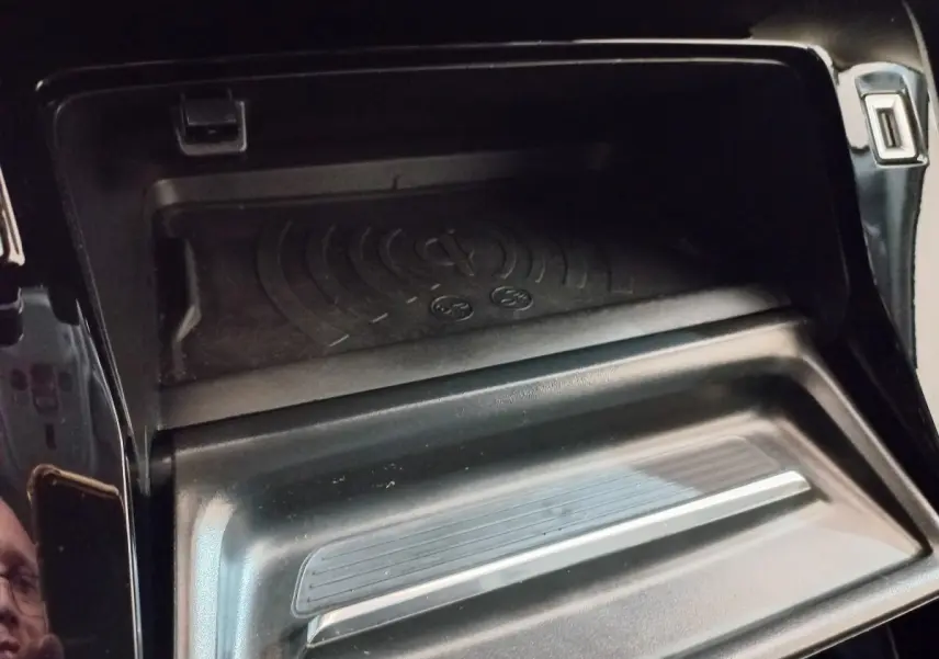 Gros plan sur la zone de recharge par induction noire dans l'habitacle du Peugeot 2008 Orange 2021.