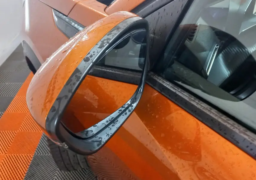 Rétroviseur côté gauche orange de Peugeot 2008 BlueHDi 110 2021 avec gouttes d'eau sur carrosserie et miroir.