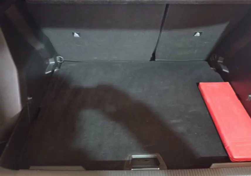 Coffre noir vu de face du Peugeot 2008 2021 avec un kit de sécurité rouge posé à droite.