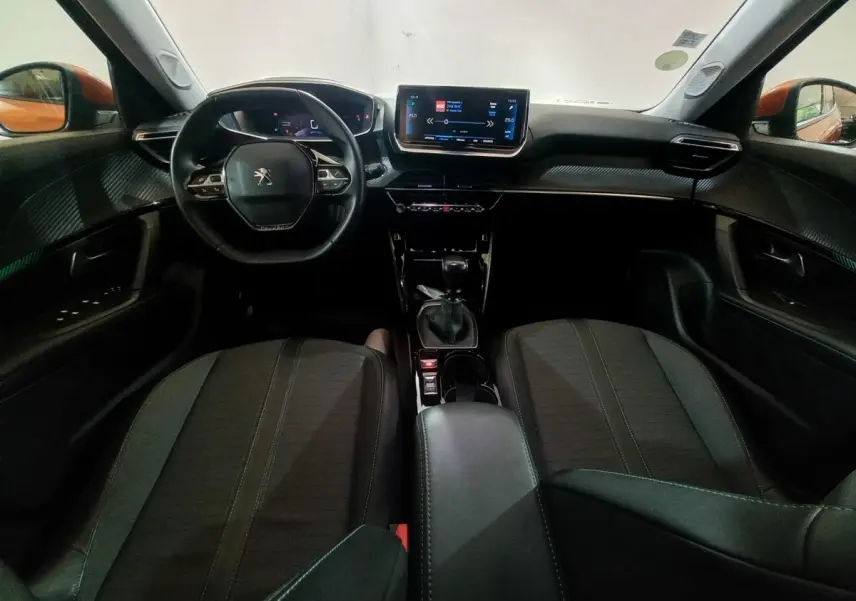 Intérieur du Peugeot 2008 orange 2021 vu de face, tableau de bord moderne avec écran tactile 10 pouces et volant cuir.