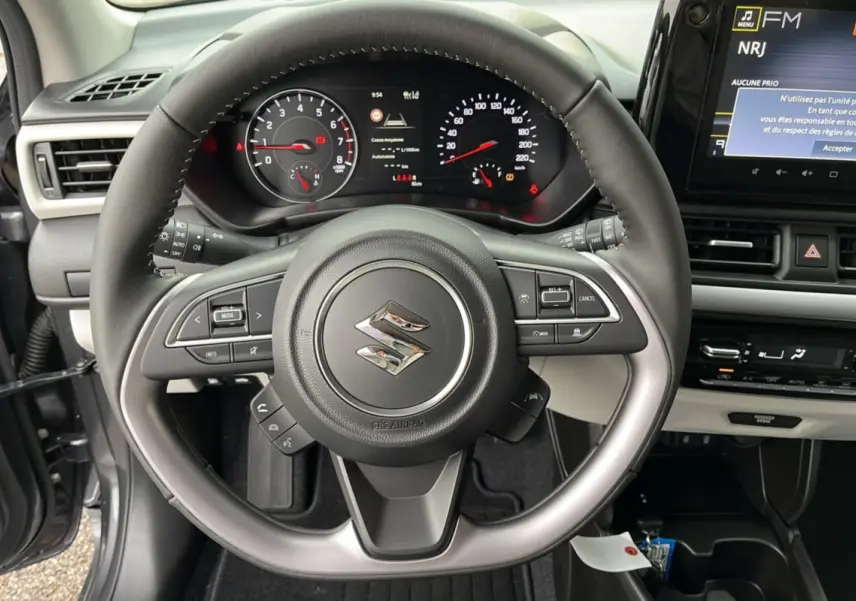 Vue centrée sur le volant cuir multifonctions d'une Suzuki Swift 2026, avec tableau de bord et écran tactile visible.